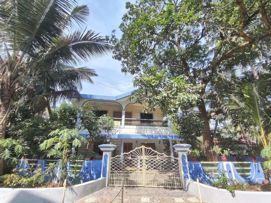 ein Haus mit einem blauen Zaun davor in der Unterkunft shirley's guest house in Majorda