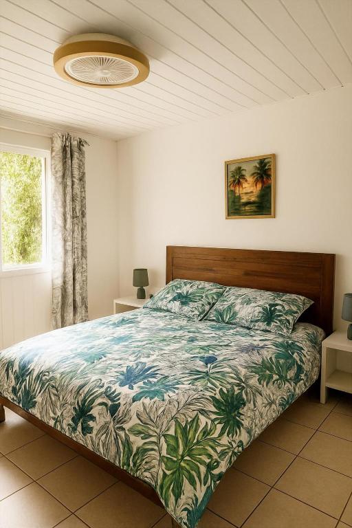 Un dormitorio con una cama con colcha tropical. en KaZen chez Steph, en Petite Île