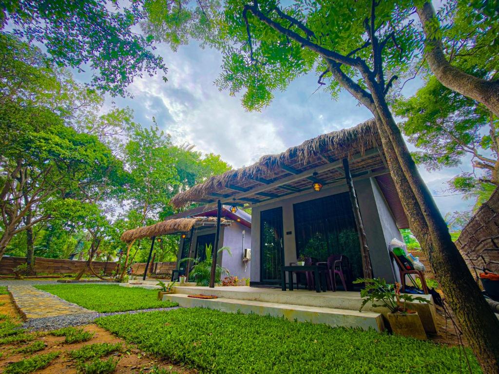 a small house with a grass roof at EMERALD HAVEN SAFARI Cottages in Udawalawe