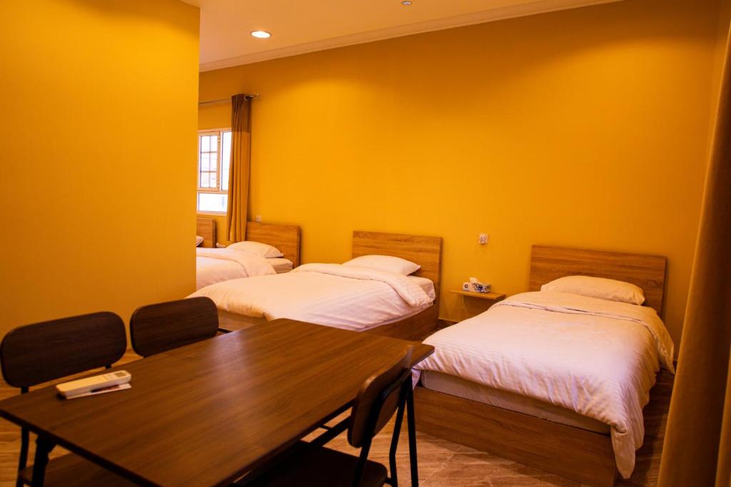 Zimmer mit 2 Betten und einem Tisch mit Stühlen in der Unterkunft The Garden Inn نزل الحدیقة in Nizwa