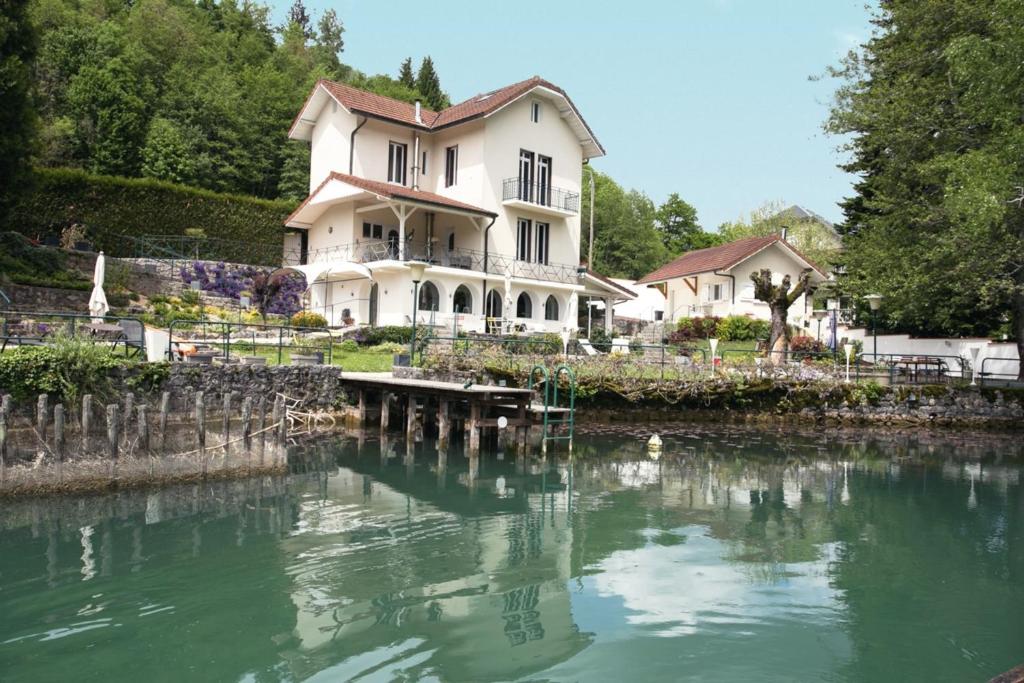 una grande casa bianca seduta accanto a un fiume di Les Nénuphars magnifique villa au bord du canal a Saint-Alban-de-Montbel