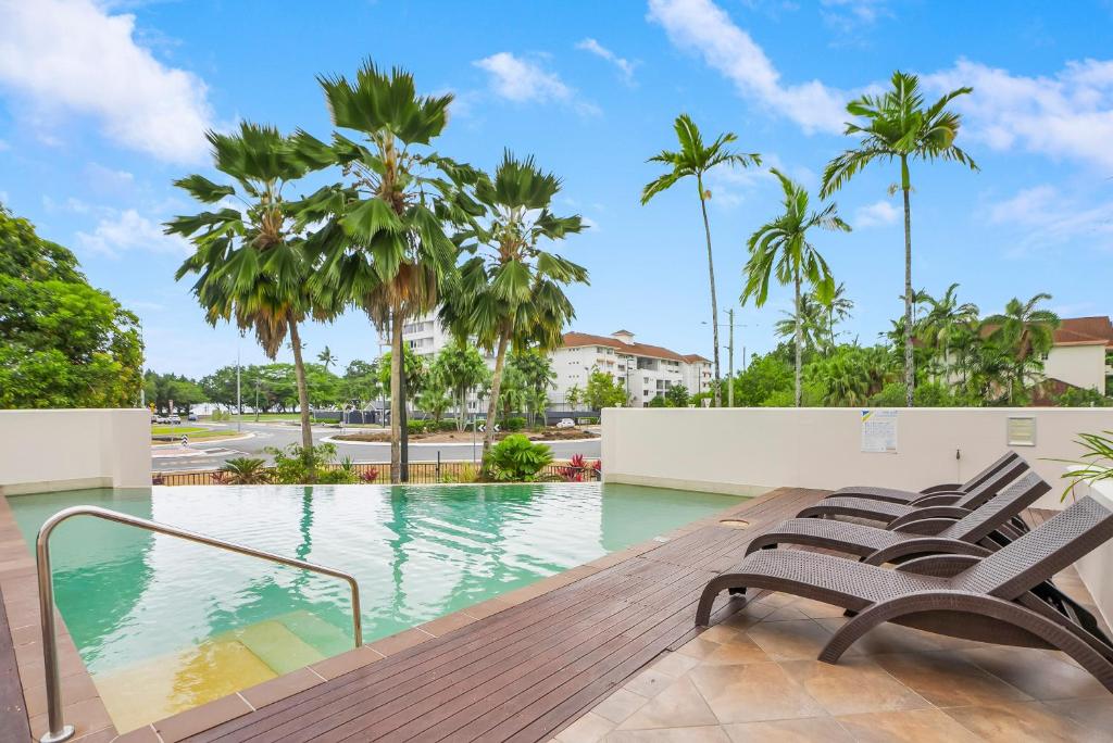 a swimming pool with chairs and palm trees at Allure at The Edge 3brm luxury apartment with coffee machine and 2 pools! in Cairns North