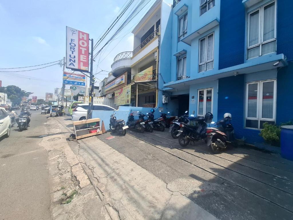 Un grupo de motocicletas estacionadas afuera de un edificio azul. en Tamastu Hotel Fortuna Jatiwaringin, en Pangkalan