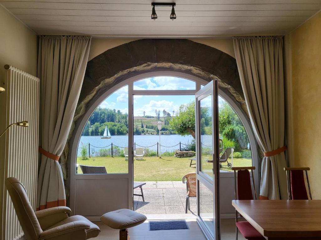 a living room with an arched doorway with a view of a lake at Strandhof Möhnesee in Möhnesee