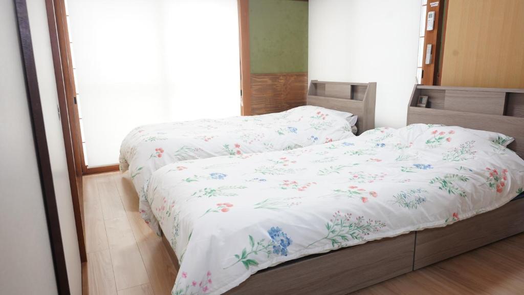 a bedroom with a bed with white sheets and flowers at PANARI guest house NISHIHONMACHI in Ube