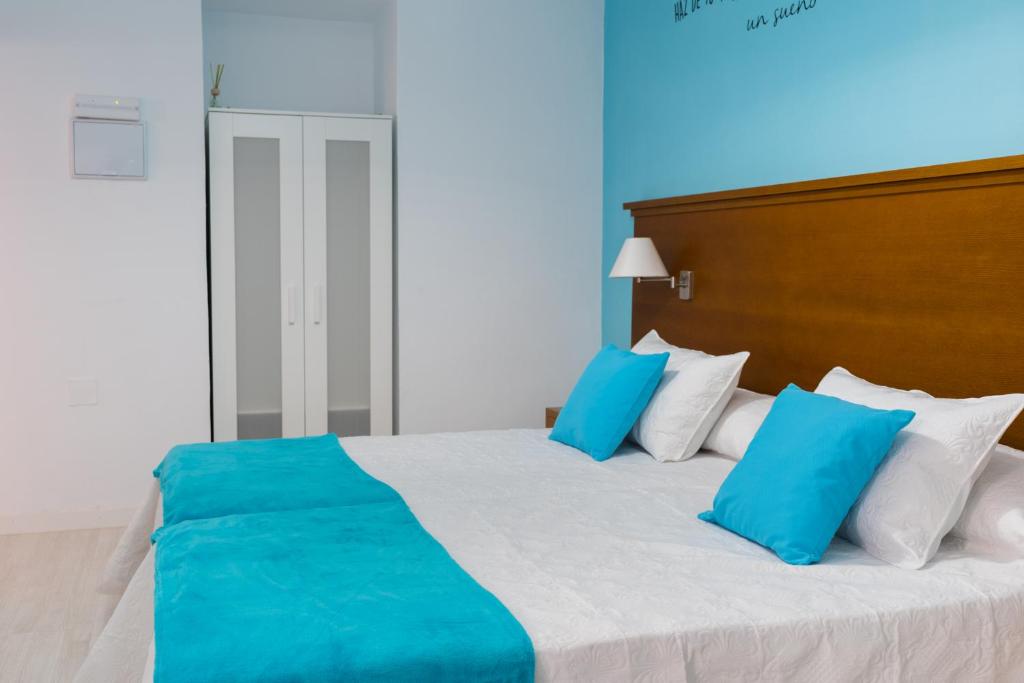 a bedroom with a large bed with blue and white pillows at Hostal Imperial centro de Mérida in Mérida