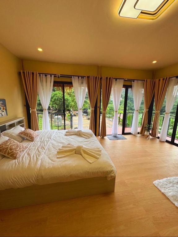 a bedroom with a bed and large windows at บ้านสวนผาหมี in Ban Nong Chaeng
