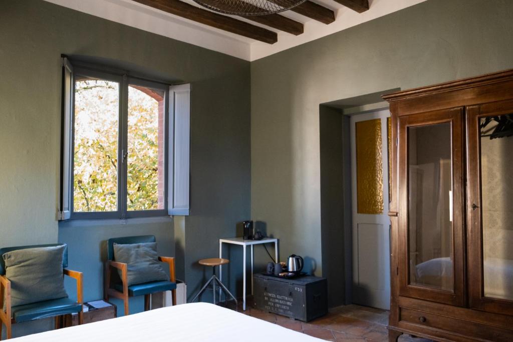 sypialnia z krzesłami, łóżkiem i oknem w obiekcie La Locanda di Grazzano Visconti w mieście Grazzano Visconti