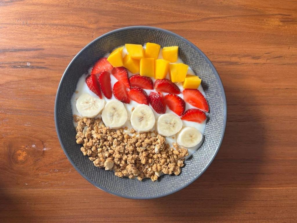 a bowl of cereal with fruit and nuts on a table at Kali Code Home in Yogyakarta