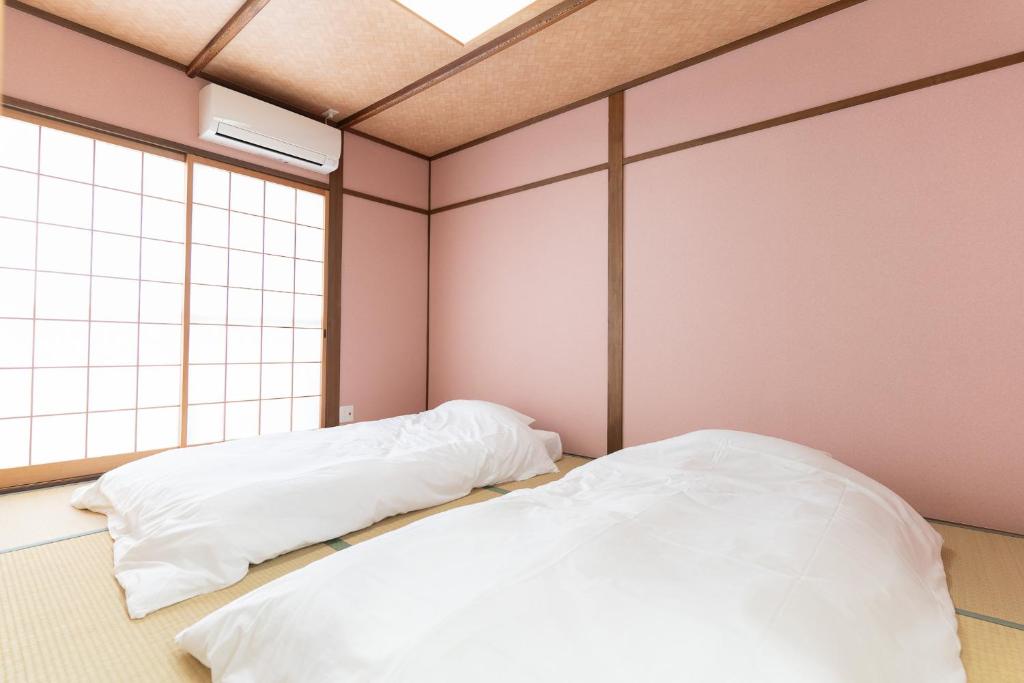 two beds in a room with pink walls at 蛮子民宿 金閣寺 in Kyoto