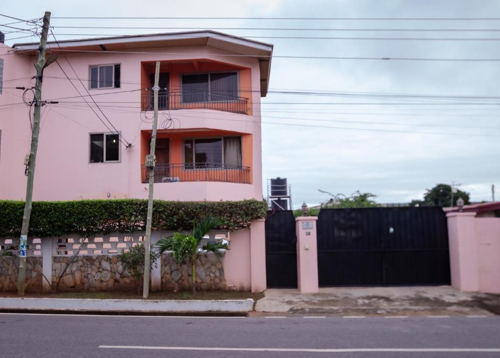 a pink house with a black fence at VERA's TOWERS in Accra
