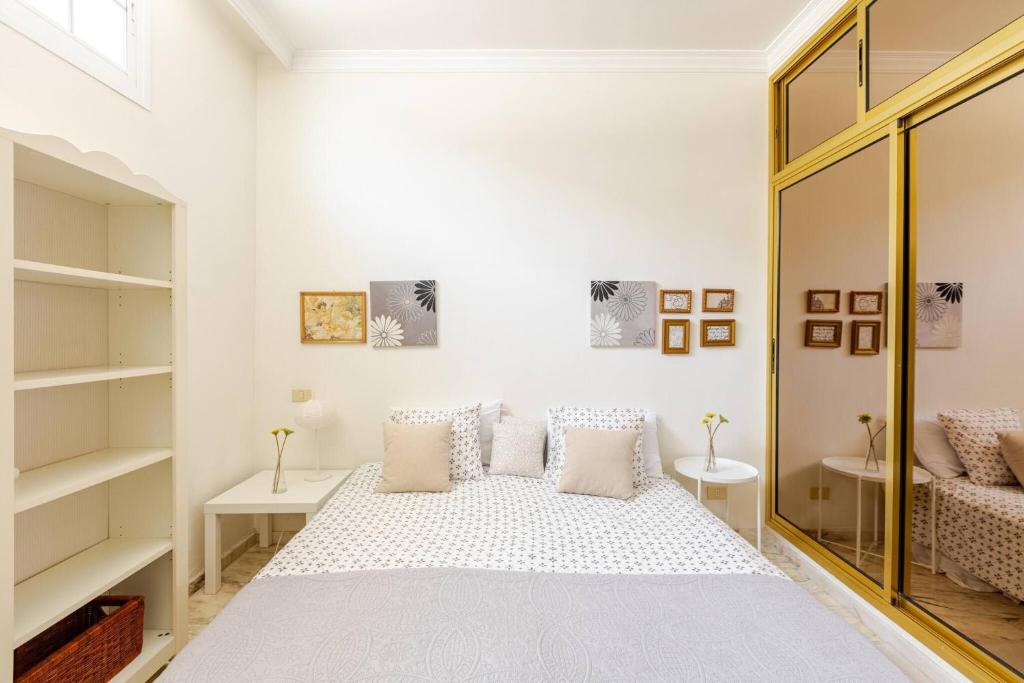 a white bedroom with a bed and a mirror at Escape To your Private Pool, Sea Views and Bbq in Jinámar