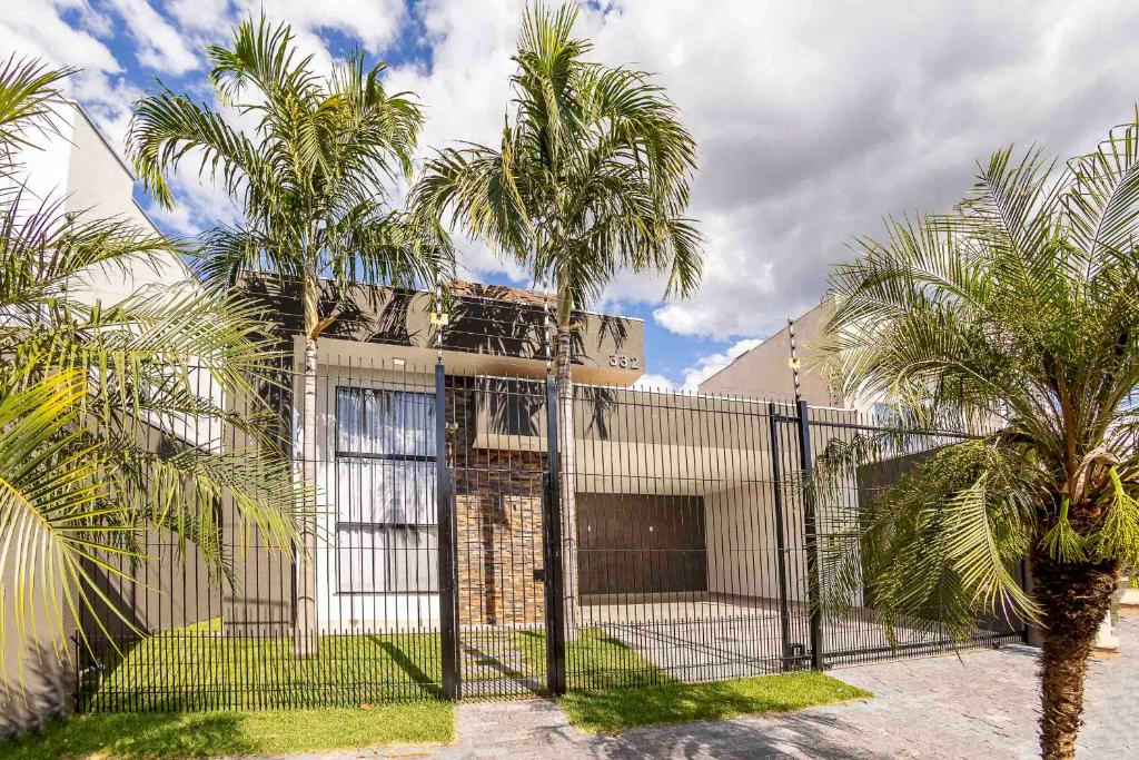 una casa con palme di fronte a una recinzione di Casa Munique Maringa a Maringá
