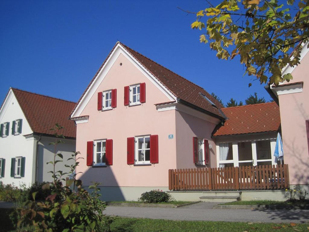 una gran casa rosa con persianas rojas en Ferienhaus Bad Waltersdorf en Bad Waltersdorf