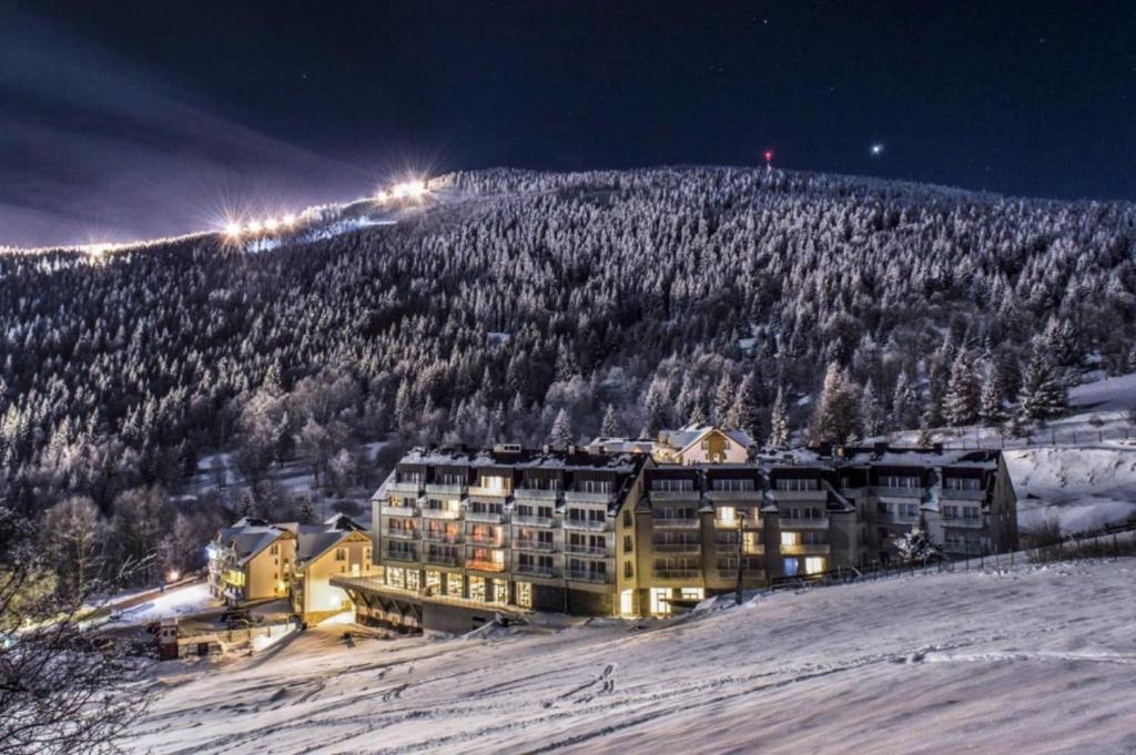 ein Gebäude auf einem schneebedeckten Berg in der Nacht in der Unterkunft Apartamenty Biała Sowa Czarna Góra in Heudorf