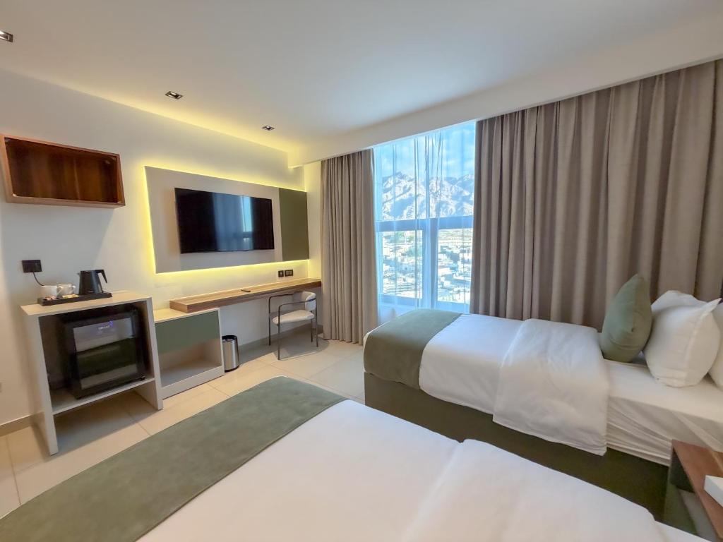 亚喀巴Coral Beach Hotel & Spa的有两张床和一台电视的酒店房间