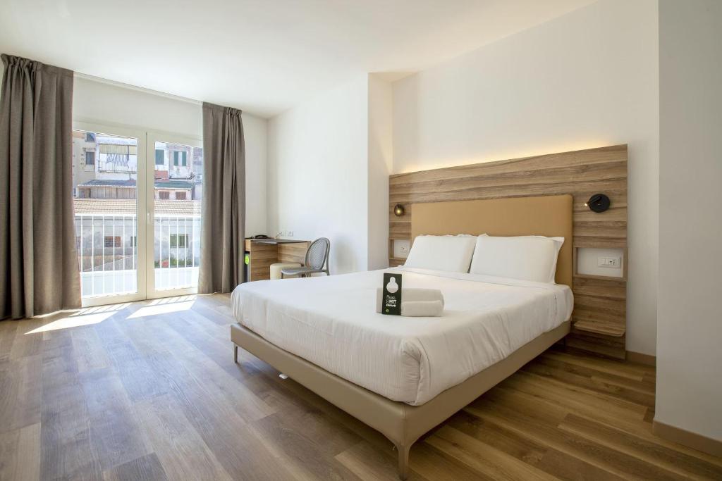 a bedroom with a large bed and a large window at B&B HOTEL Sassari in Sassari