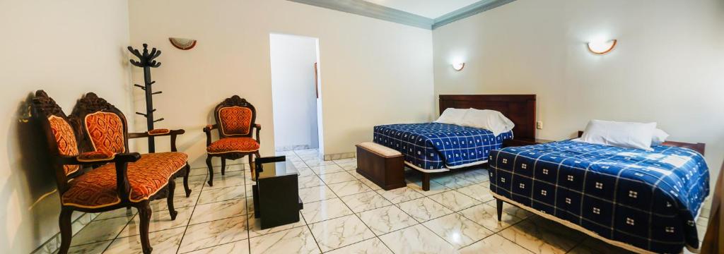 Habitación con 2 camas y 2 sillas. en Hostal El Remanso en Arequipa