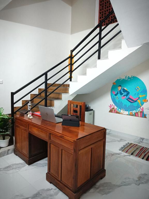 a desk with a laptop on it in a room with stairs at Sandora Home Stay in Varkala