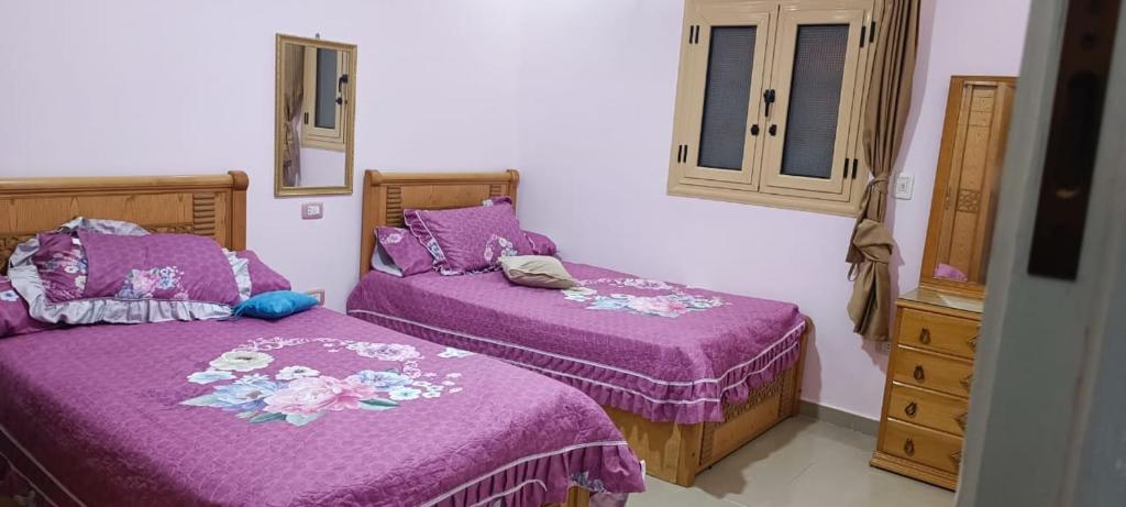 Un dormitorio con dos camas con colchas moradas y una cómoda. en شقه فاخره على الكورنيش للعائلات فقط, en Alejandría