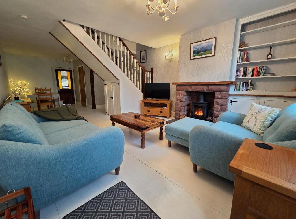 a living room with two blue couches and a fireplace at Feather Bed Cottage - Dog Friendly Lakeland Retreat with Log Burner & Garden in Brayton Station