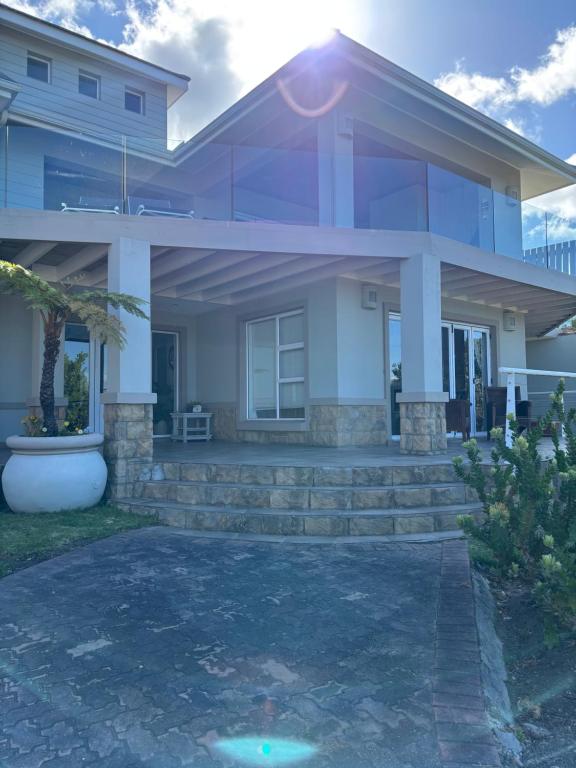 a large white house with stairs in front of it at Hill Top Guesthouse in Plettenberg Bay