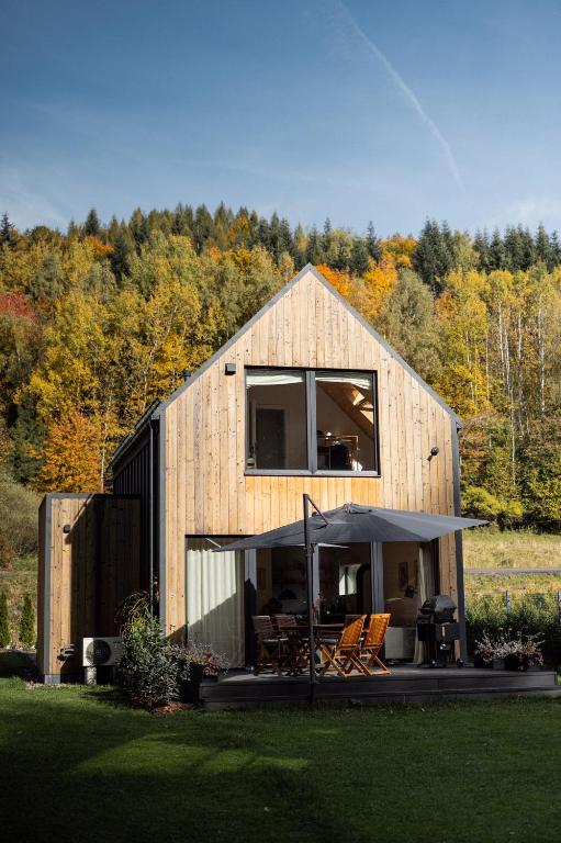 a wooden house with a patio and an umbrella at Babia Rest - całoroczny domek z balią z jacuzzi in Zawoja