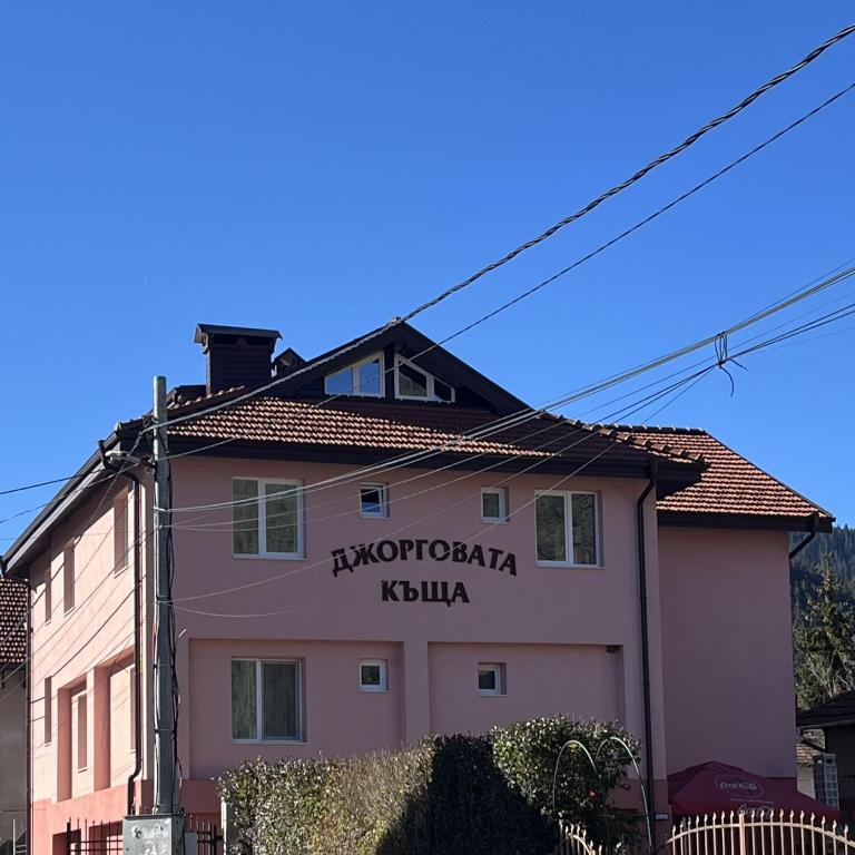 a pink building with a sign on the side of it at Dzhorgovata Guesthouse in Govedartsi