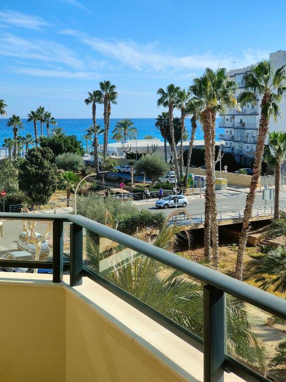 a balcony with a view of the beach and palm trees at Albir Beach Apt in Albir