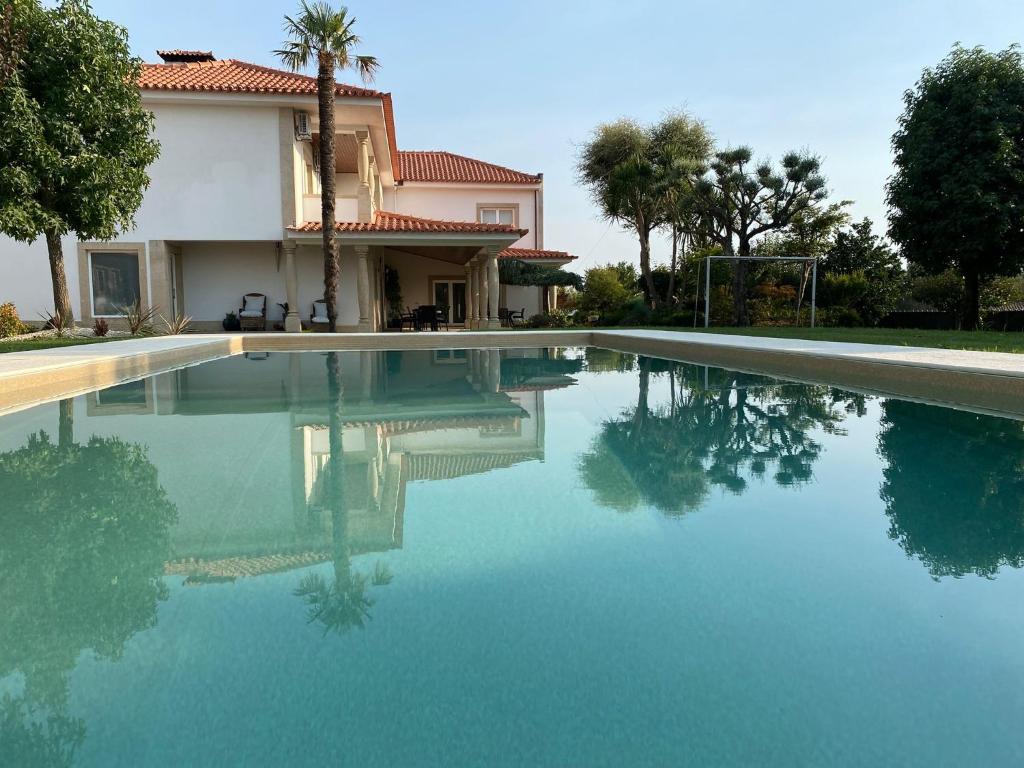 a swimming pool with blue water in front of a house at Camélias Casa de Charme in Varziela