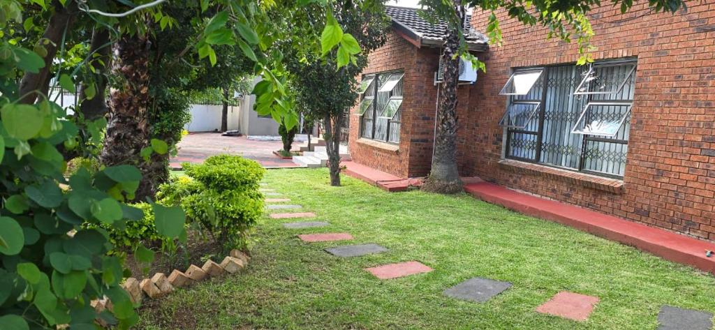 Mogwasekiddy的一栋砖砌房屋，带有一个长满草坪和树木的院子。