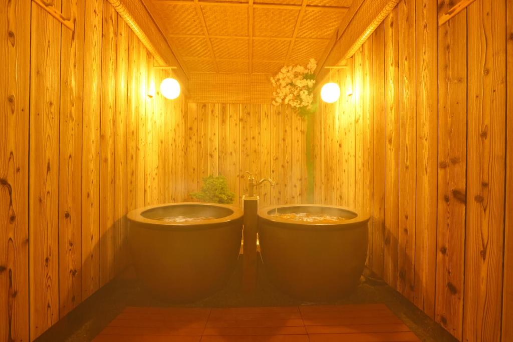 a bathroom with two sinks in a wooden wall at 庭音日和 2つの半露天壺湯でくつろぐ宿 大家族向け広々一棟貸し 駐車場2台 浴室2箇所 in Omihachiman