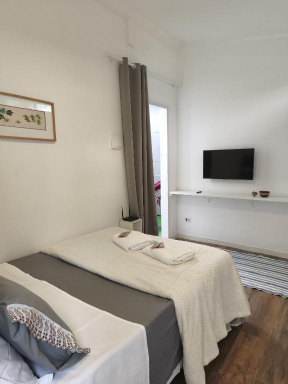 a bedroom with two beds and a tv on the wall at Suíte privativa Vila Dom Pedro in Paraty