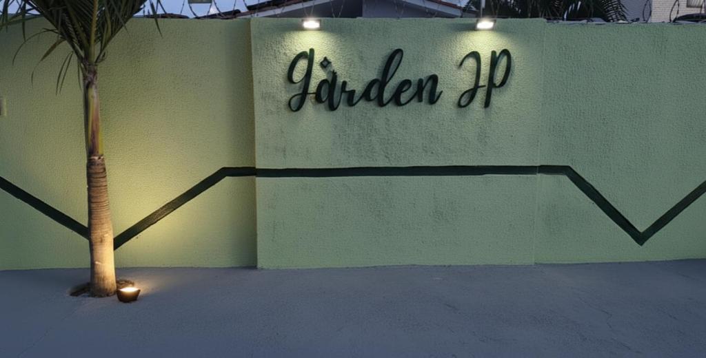 Eine Palme vor einer Mauer mit einem Schild in der Unterkunft Garden JP in João Pessoa