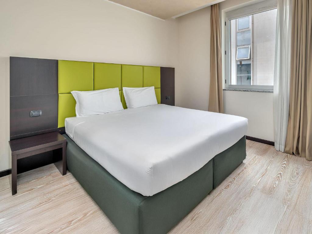 a bedroom with a large bed with a green headboard at B&B HOTEL Park Hotel Cassano in Cassano dʼAdda