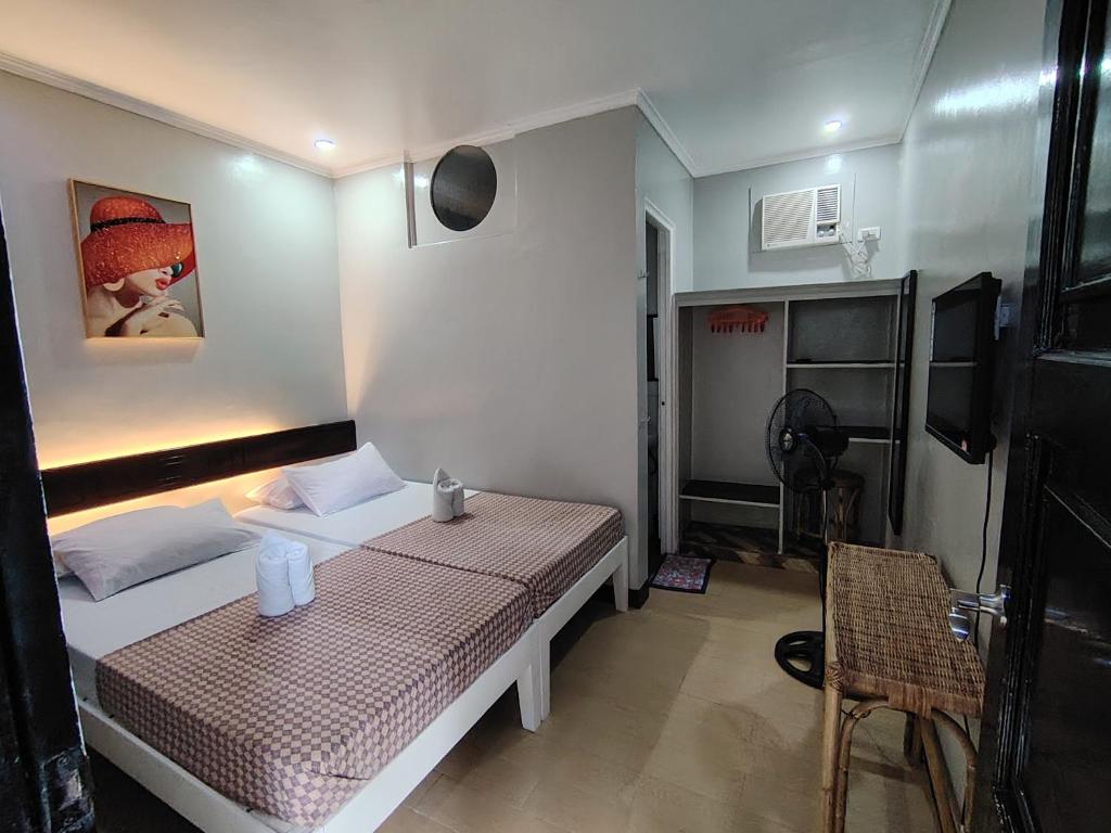 Un pequeño dormitorio con una cama y una mesa. en Joaquinn's Bed and Breakfast, en El Nido