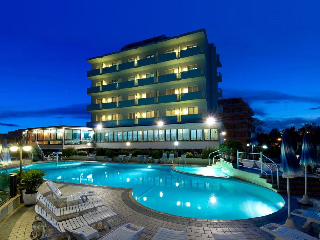 a swimming pool in front of a building at night at Strand Hotel Colorado in Lido di Savio