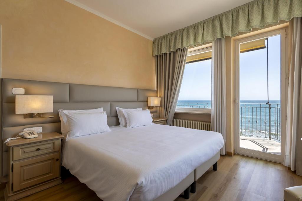 Un dormitorio con una cama grande y una ventana grande en B&B HOTEL Diano Marina Palace, en Diano Marina