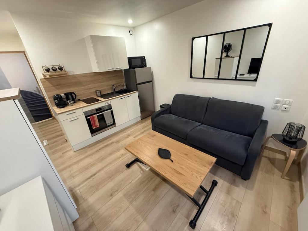a living room with a black couch and a table at Studio cozy à Lagnieu in Lagnieu