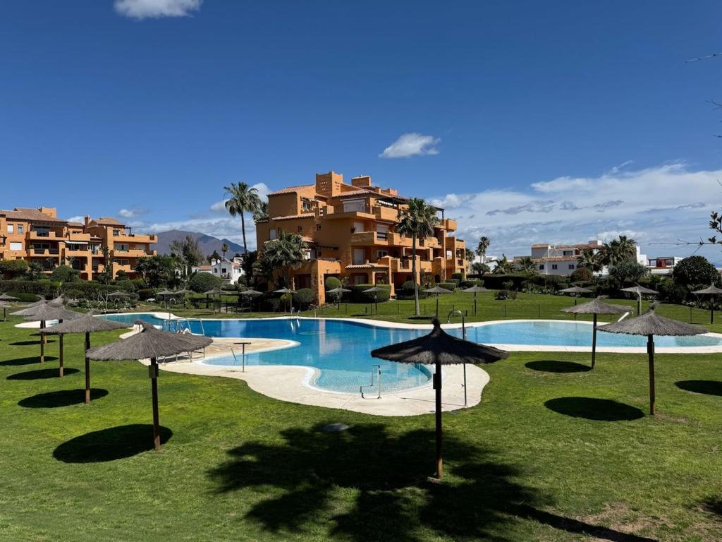 a large swimming pool with umbrellas in front of a building at Los Granados Stunning 2 Bed Beach Apartment in San Luis de Sabinillas