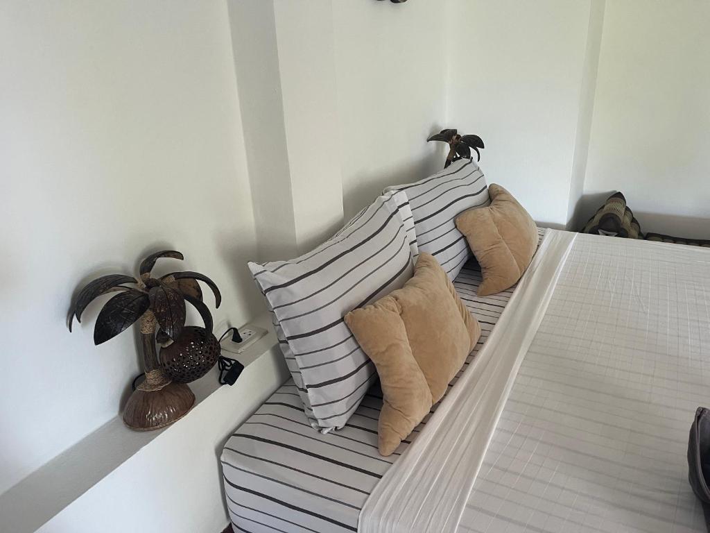 un letto con tre cuscini e una pianta sopra di Pink House a Lamai Beach