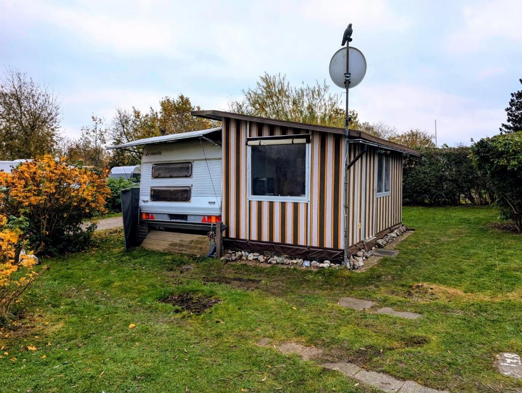 una casetta è parcheggiata in un cortile di Wohnwagen mit feststehendem Vorzelt a Fehmarn