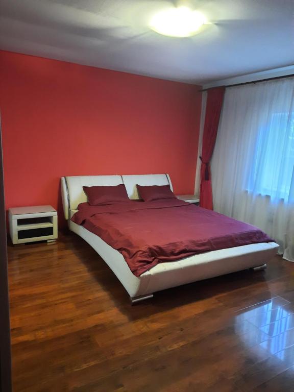 ein Schlafzimmer mit einem Bett mit einer roten Wand in der Unterkunft MihaiResidence in Craiova