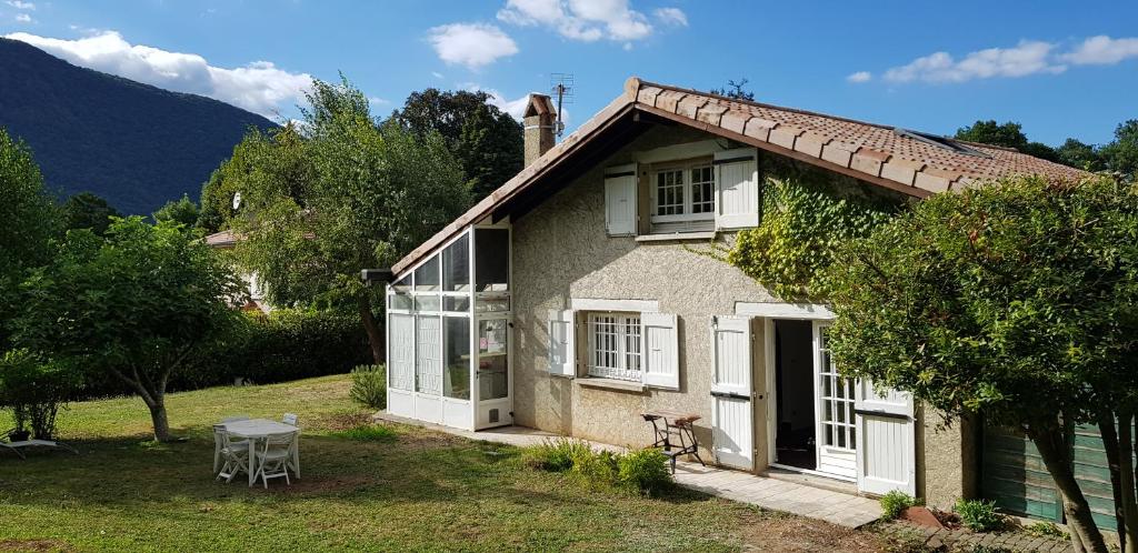 a small house with white windows and a table at Chambres cosy au hameau de St Pierre in Saint-Georges-de-Commiers