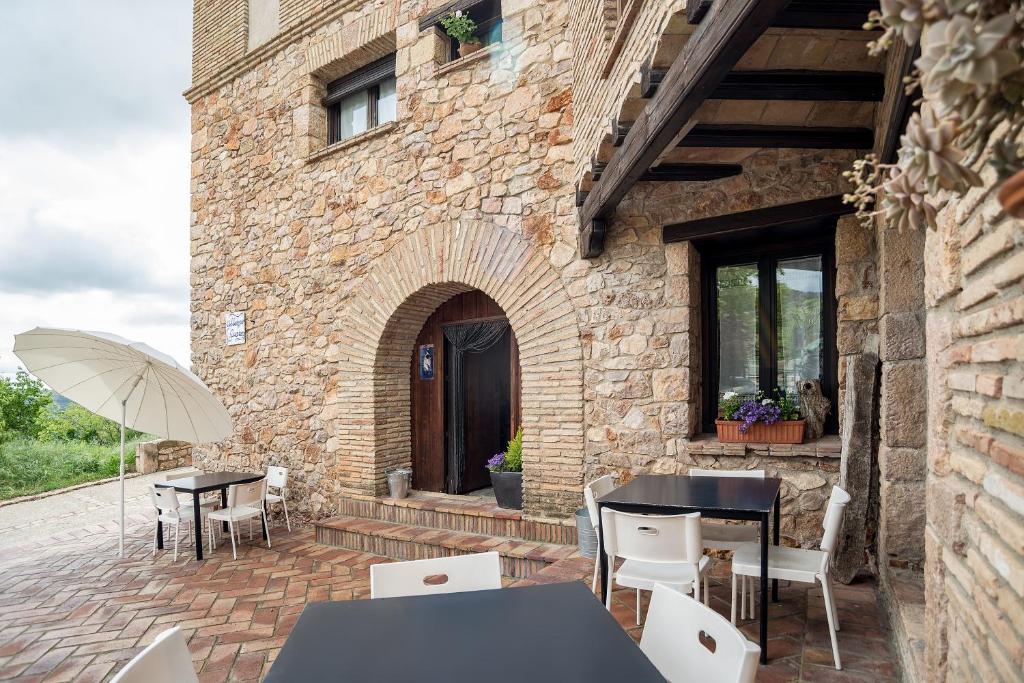 アルケサルにあるAlbergue Rural de Guaraのテーブルと椅子と傘のあるパティオ