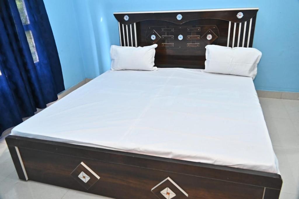 a bed with a wooden headboard and white sheets at Royal hotel in Hardoī