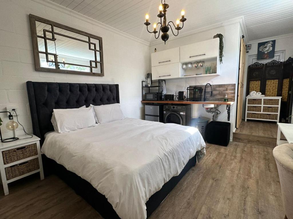 a bedroom with a large bed and a chandelier at Studio Seabiscuit in Cape Town