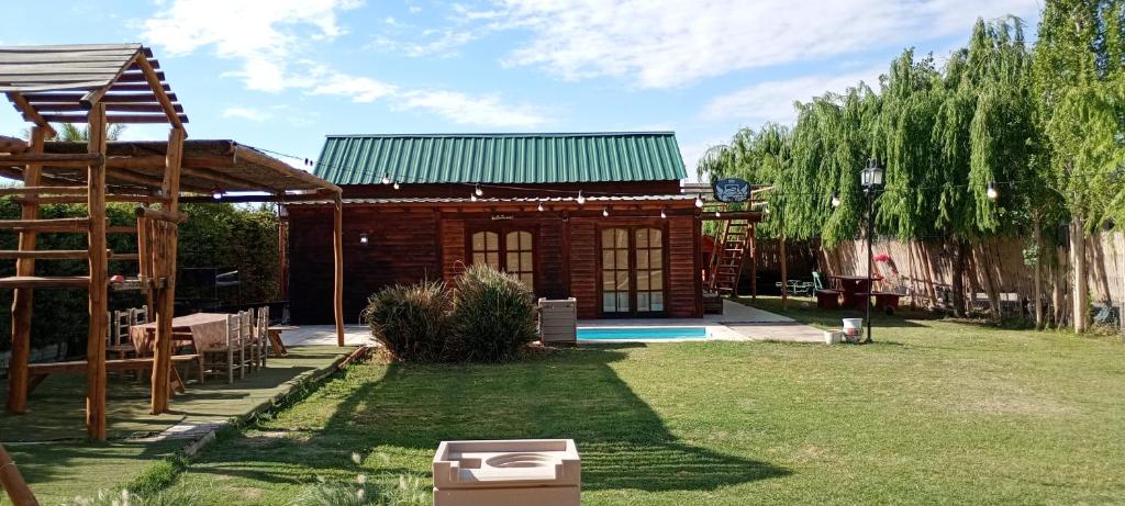 a small wooden house with a green roof at Cabaña los Sauces in Rivadavia