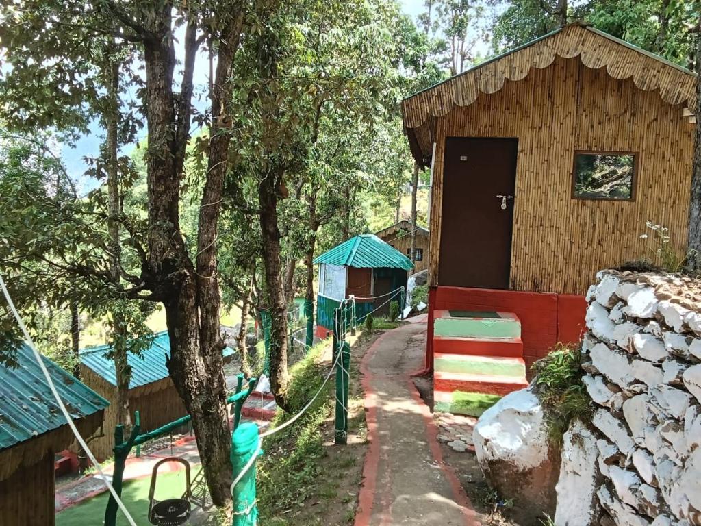 ein kleines Holzgebäude mit einer Tür und einem Zaun in der Unterkunft TTN - The Trekker's Nest in Jyotirmath