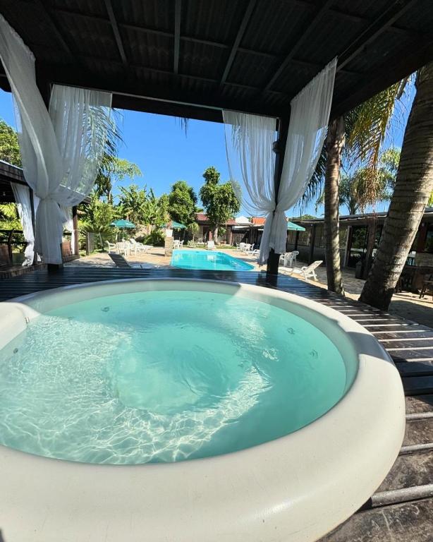 a jacuzzi tub under a pavilion with a beach at Recanto Carvalho - Suíte 2 in Itapoa